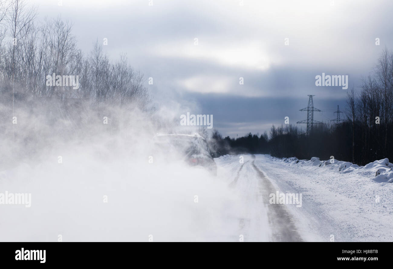 Das Auto beim Überholen hat eine Schleife von Schnee Staub befreit. Schlechten Sichtverhältnissen. Gefährliche glatte Straße. Stockfoto