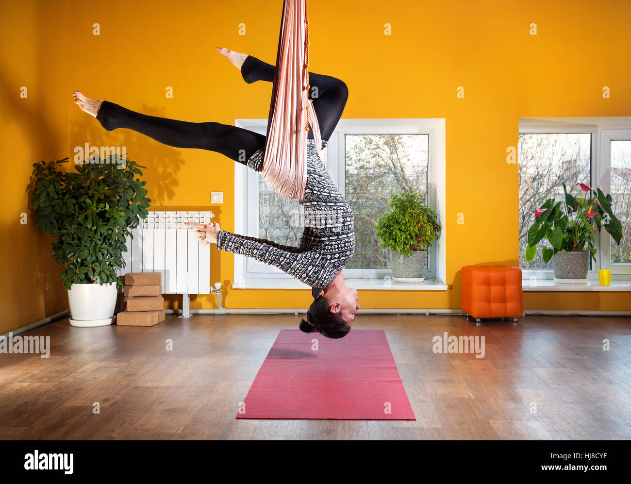 Junge Frau Antigravity Yoga im Wellnessstudio mit gelben Wänden zu tun Stockfoto
