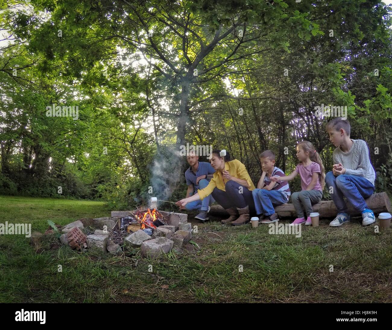 Familie sitzt am Lagerfeuer Marshmallows rösten Stockfoto