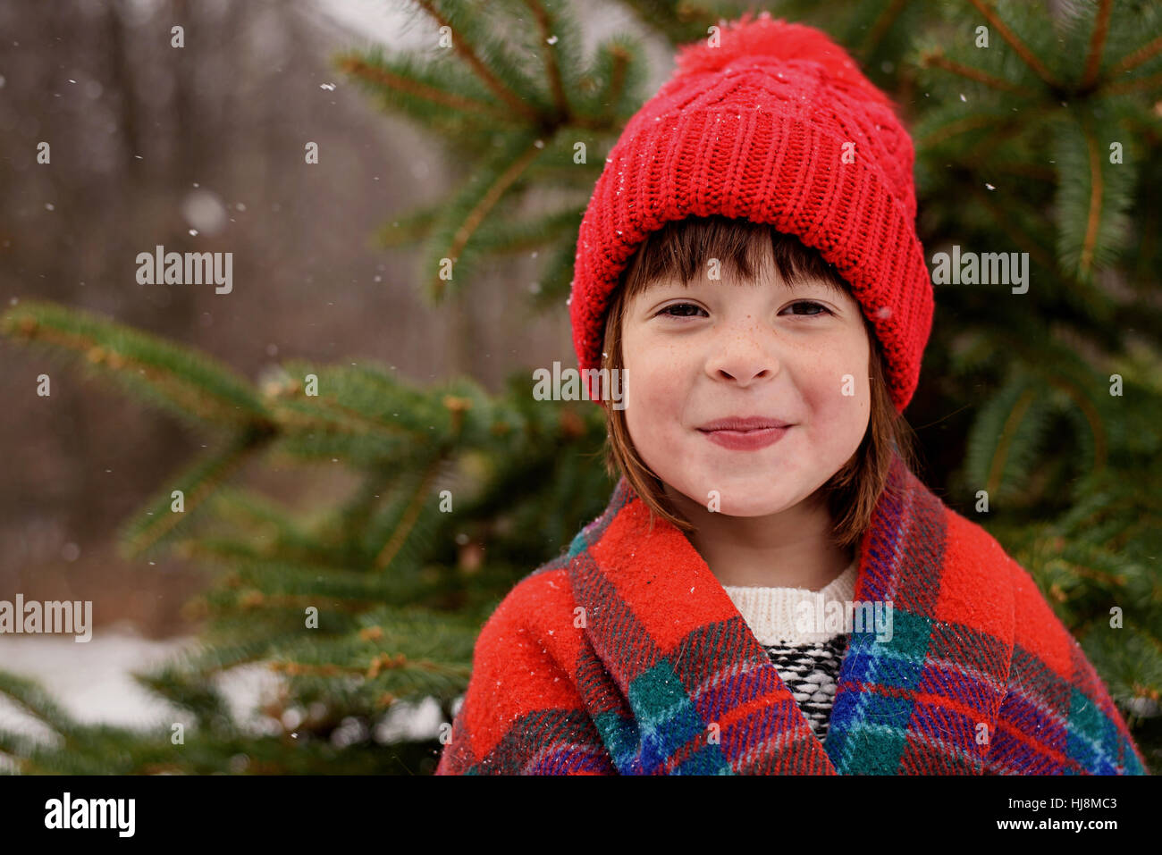 Porträt eines Mädchens, eingewickelt in eine Decke vor einem Weihnachtsbaum stand Stockfoto