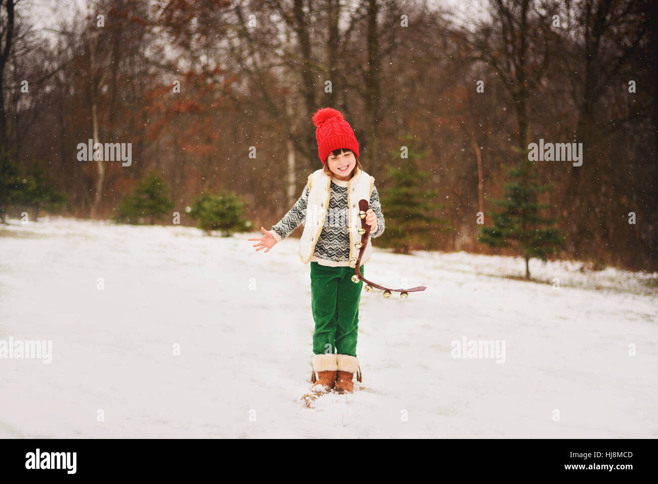 Mädchen stehen im Schnee Jingle Glocken läuten Stockfoto
