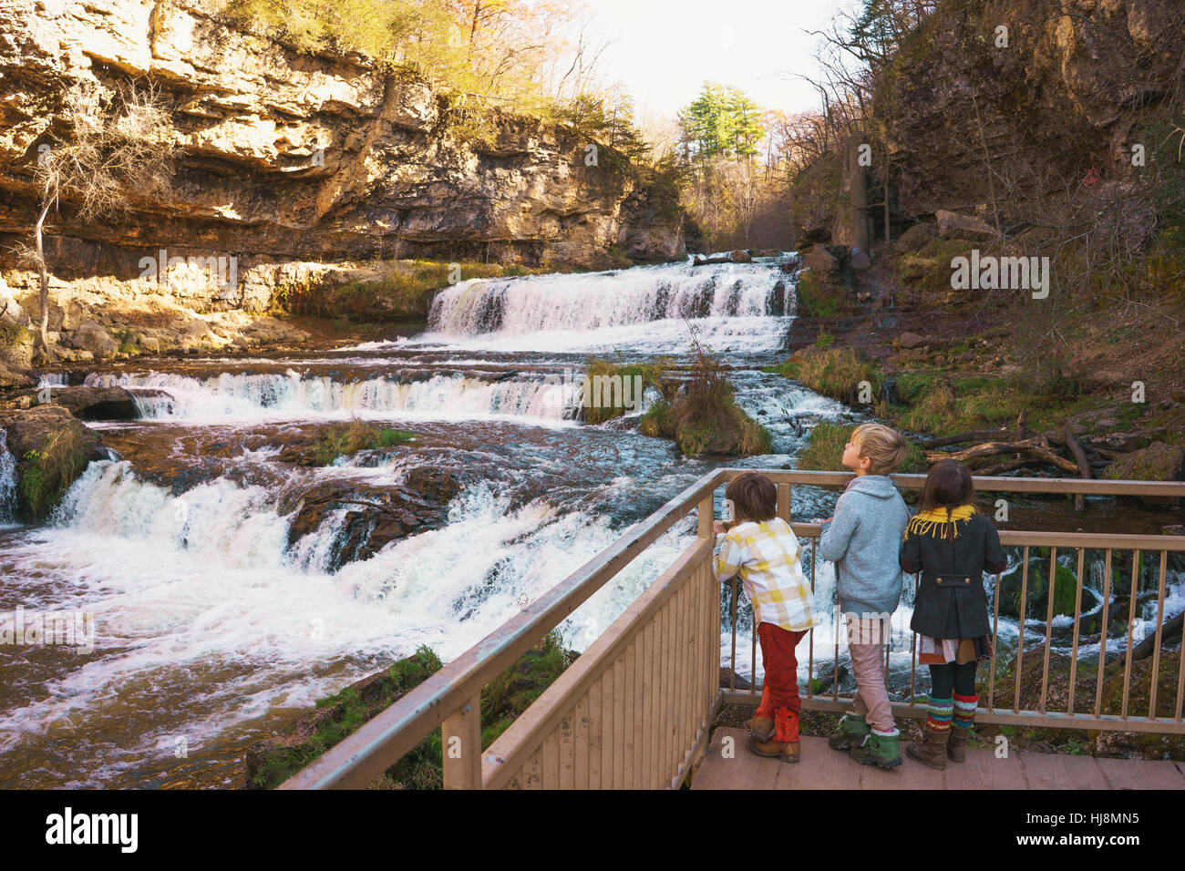 Drei Kinder auf der Suche an einem Wasserfall Stockfoto