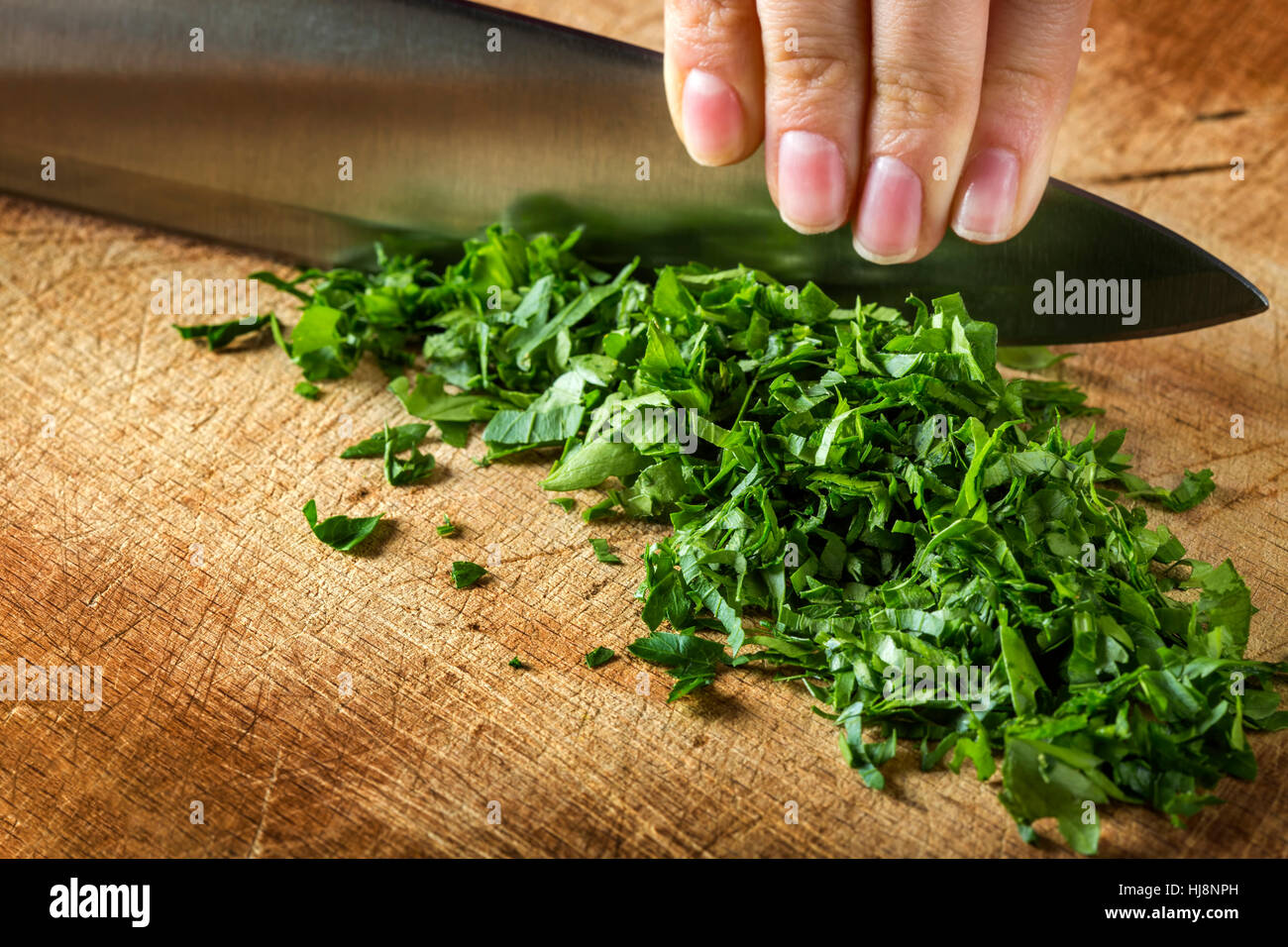 Frau Hand schneiden rohe Petersilie auf hölzernen Cutting Board Hintergrund Stockfoto