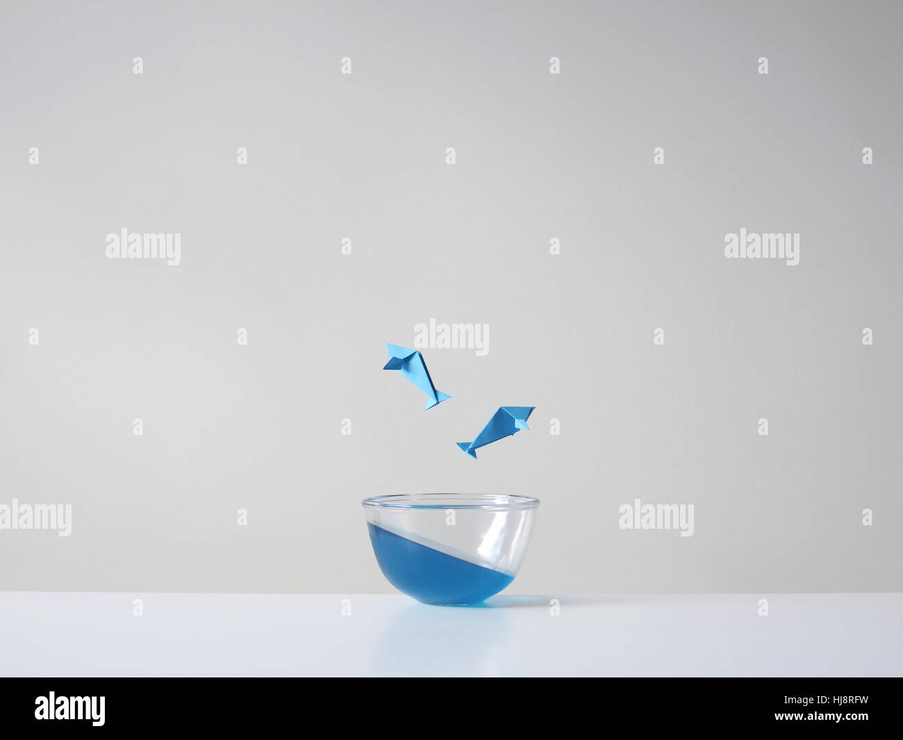 Konzeptioneller Fisch springt in einer Glasschale aus dem Wasser Stockfoto