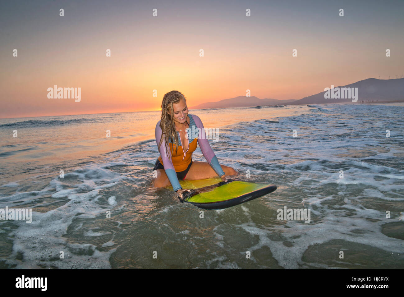 Frau sitzt auf Surfbrett, Los Lances Strand, Tarifa, Cádiz, Andalusien, Spanien Stockfoto