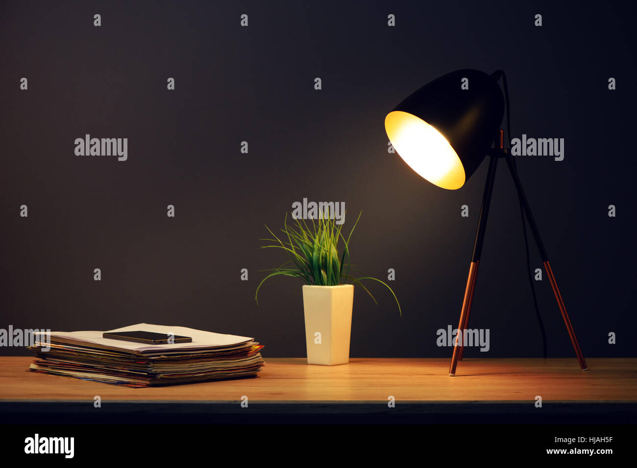 Büro Schreibtisch mit Lampe, Handy, Stapel von Zeitungen und grüne Pflanze im Topf Stockfoto