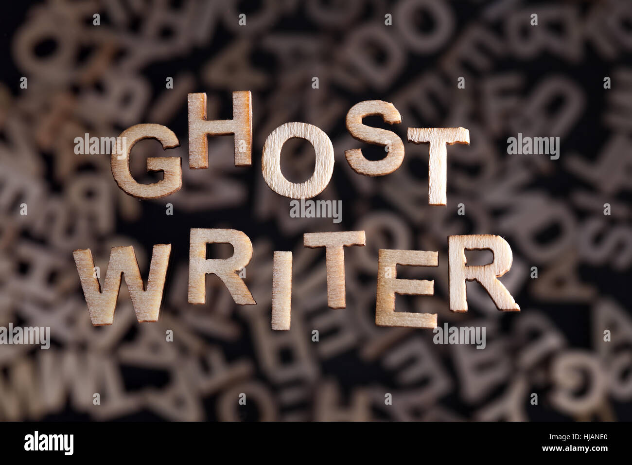 Ghostwriter-Text in Holzbuchstaben schwebt über zufällige Buchstaben unscharf Stockfoto