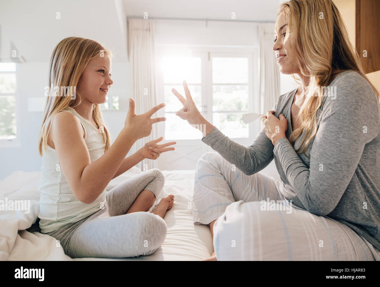 Richtungskontrolle Blick der jungen Frau spielt mit kleinen Mädchen im Bett zu Hause. Mutter und Tochter spielen im Schlafzimmer. Stockfoto