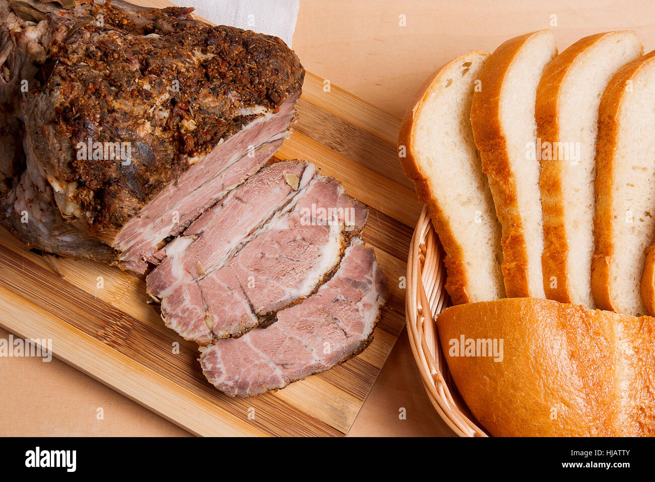 Würzige Fleisch gebacken mit Kräutern und Gewürzen auf Holzbrett. Stil überbackene würzige Landschinken. Ein saftig frisch gebackenes Schweinefleisch auf Holzbrett und Scheiben Stockfoto