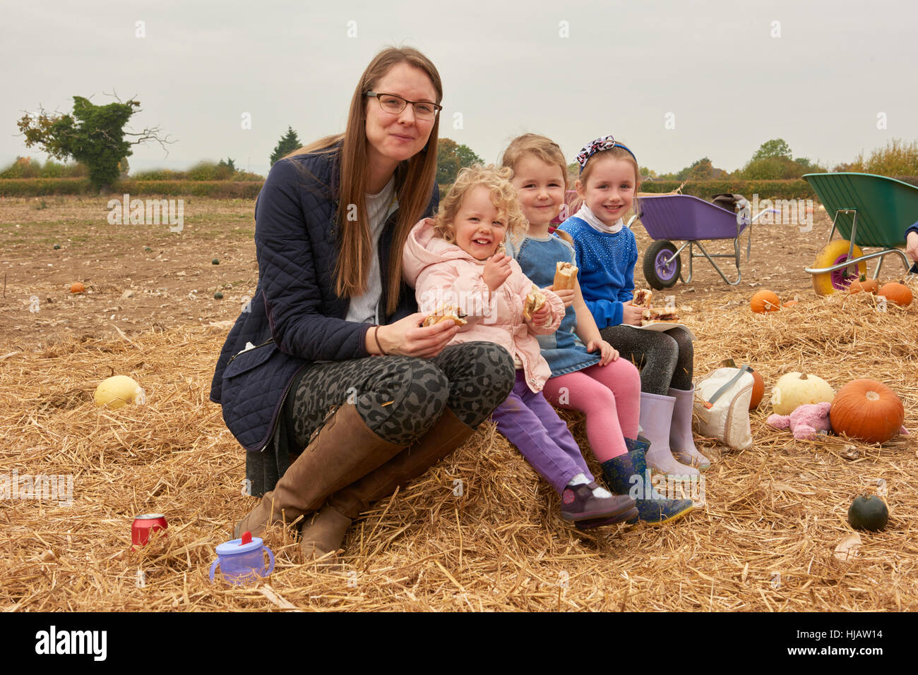 Porträt von Mitte Erwachsene Frau und drei Mädchen Picknicken in Kürbis Feld Stockfoto
