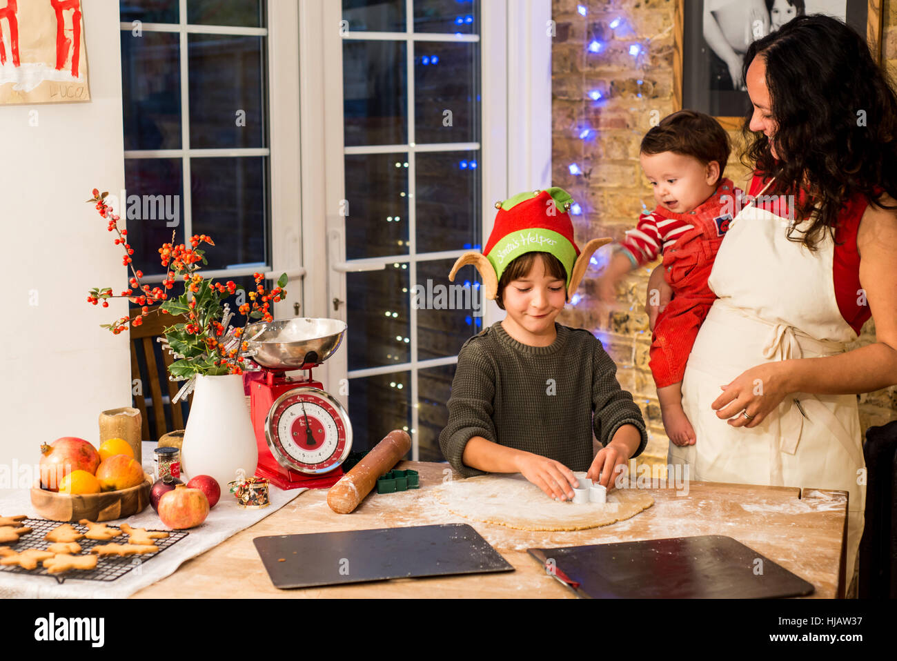 Reife Frau vorbereiten Weihnachtsplätzchen mit Söhnen am Küchentisch Stockfoto