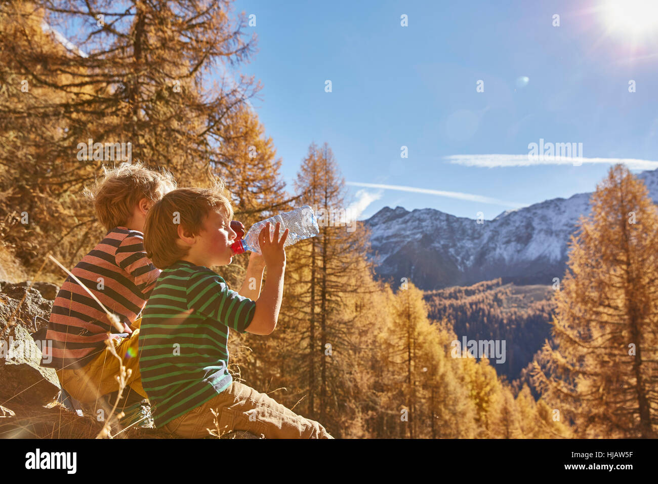Zwei Jungs sitzen auf Felsen, Trinken von Wasser in Flaschen, Schnalstal, Südtirol, Italien Stockfoto