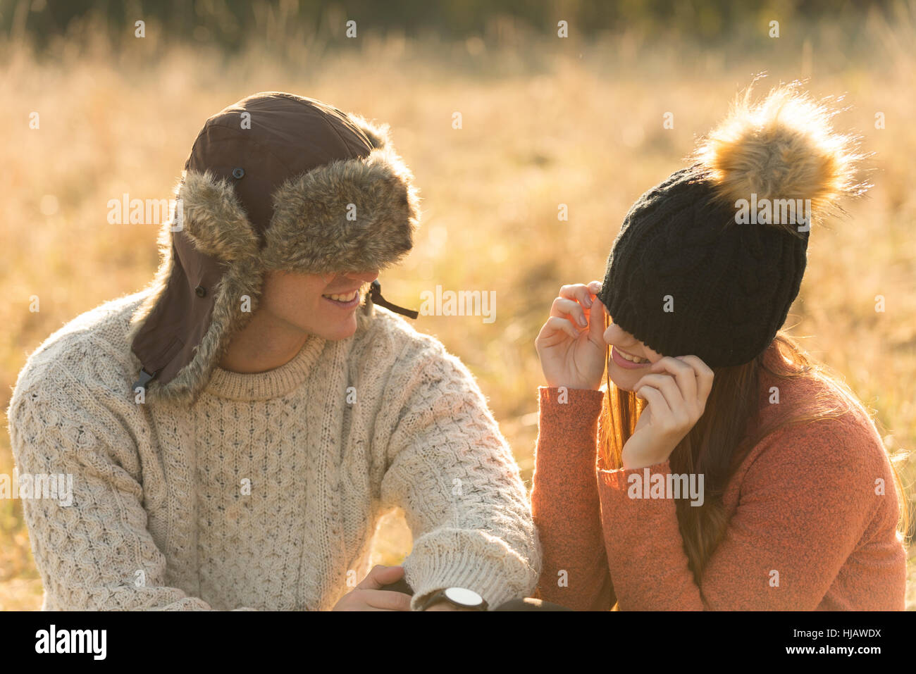 Junges Paar sitzt in ländlicher Umgebung, warme Hüte tragen Stockfoto