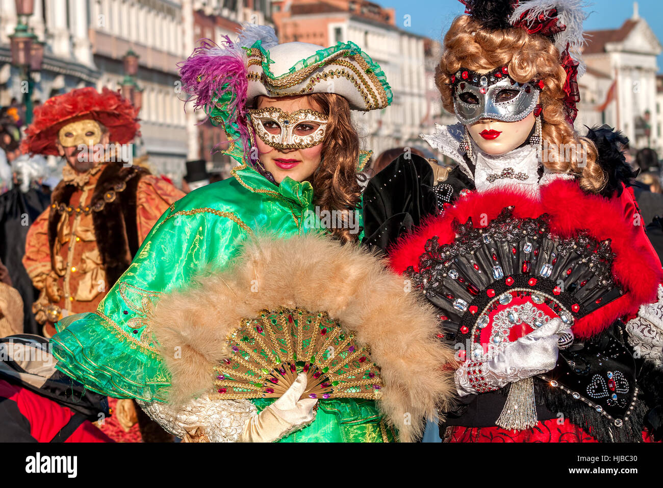 Zwei junge Frauen tragen bunte Kleider und Masken bei traditionellen berühmten Karneval legen jedes Jahr in Venedig. Stockfoto