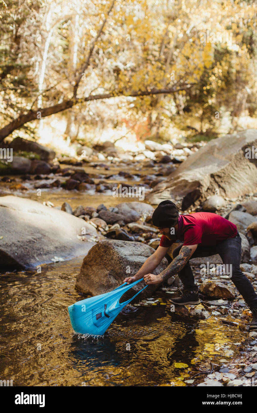 Junge männliche Wanderer Angeln mit Plastiktüte in Fluss, Mineral King, Sequoia Nationalpark, Kalifornien, USA Stockfoto