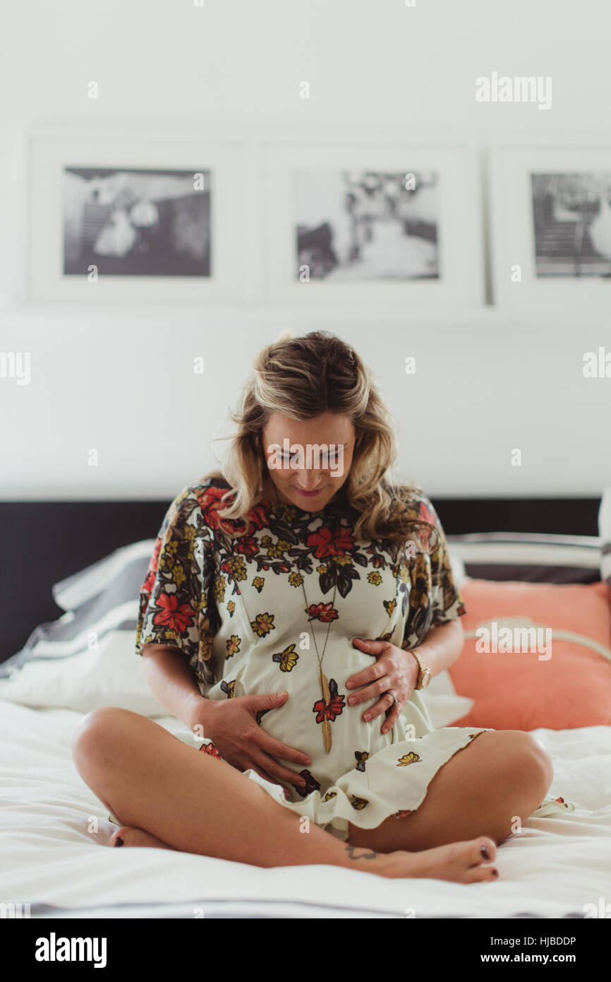 Schwangere Frau auf Bett Bauch zu berühren Stockfoto