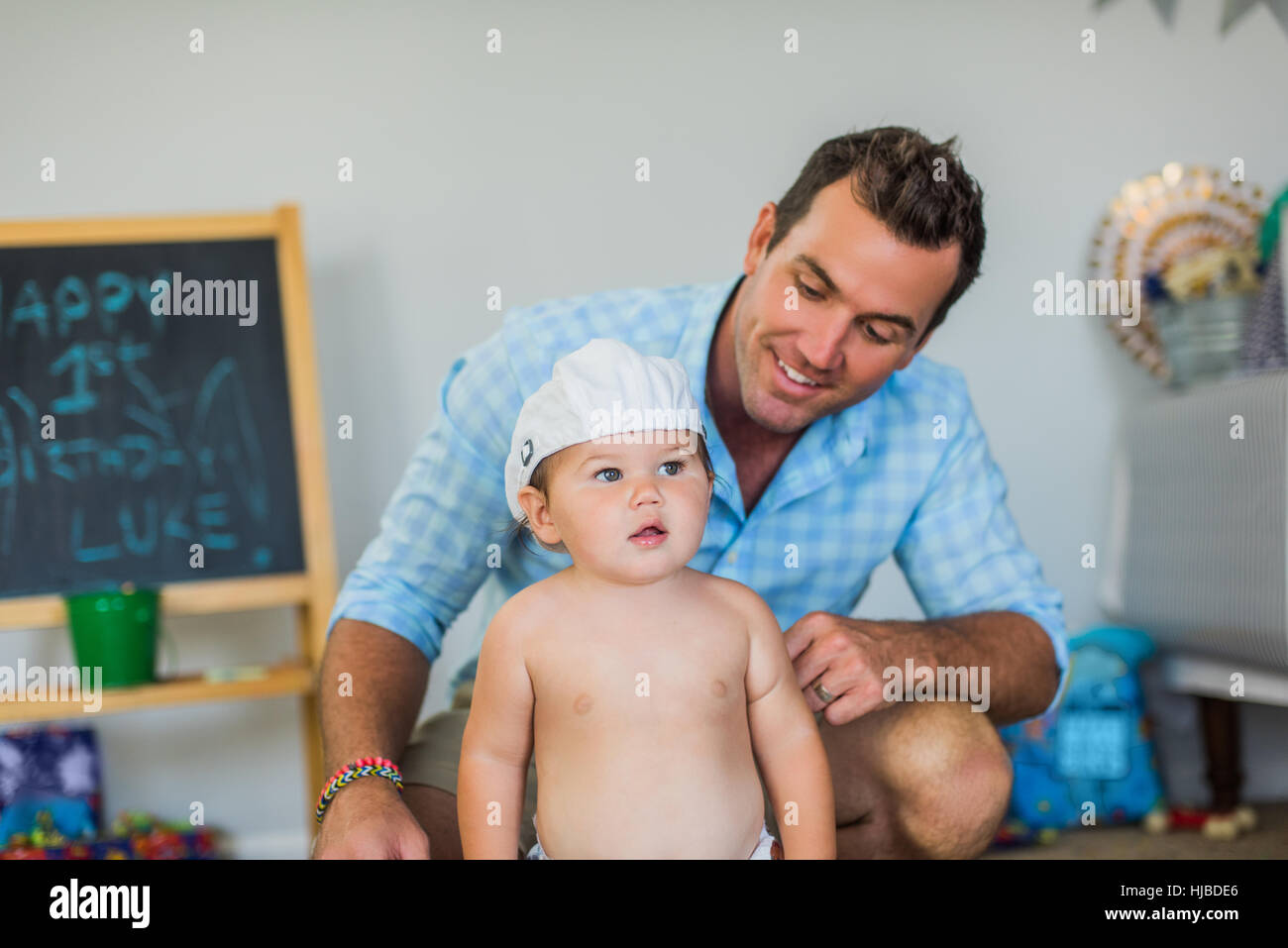 Vater lächelte Kleinkind mit lustigen Hut Stockfoto