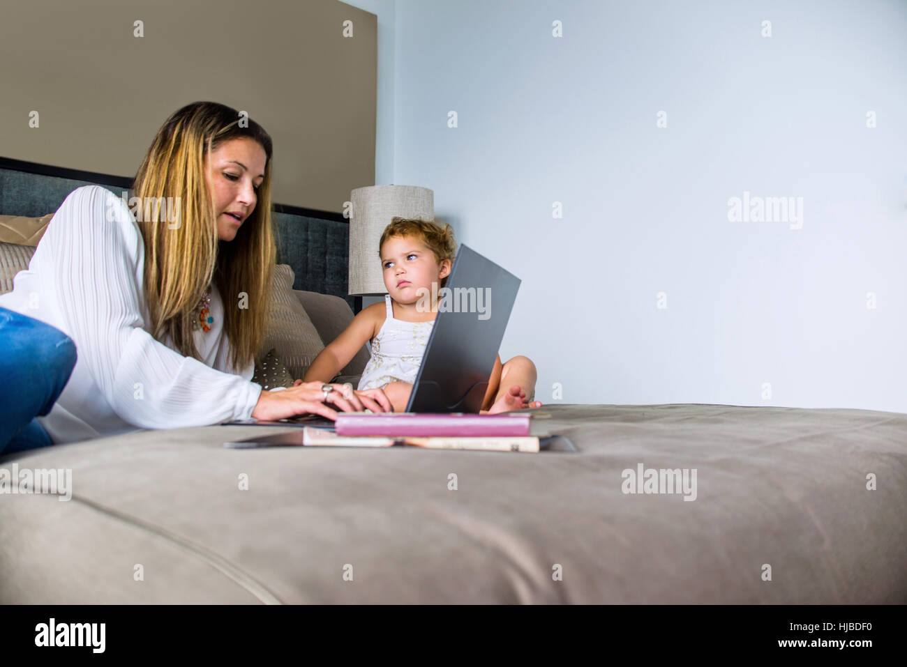 Mutter mit Laptop auf dem Bett mit Tochter Stockfoto
