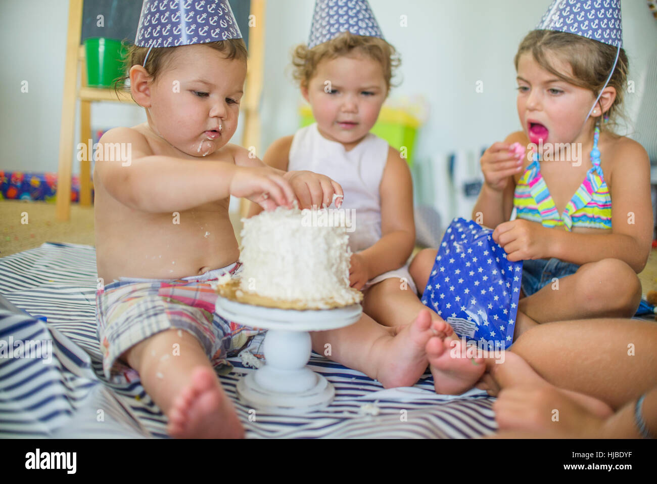 Blick auf junge stossen Finger in Geburtstagskuchen Geschwister Stockfoto