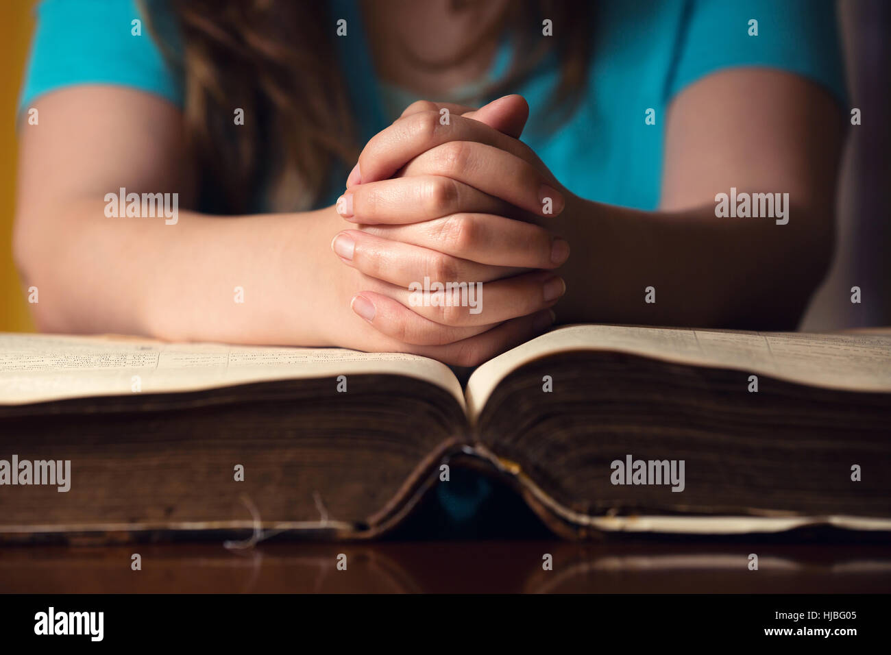 Mädchen mit den Händen auf 150 Jahre alte Bibel beten Stockfoto