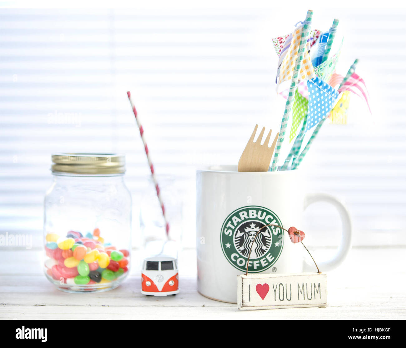 White-Starbucks-Becher mit Starbucks-Logo, VW Camper Van und Gummibärchen auf weißem Holz Hintergrund. Stockfoto