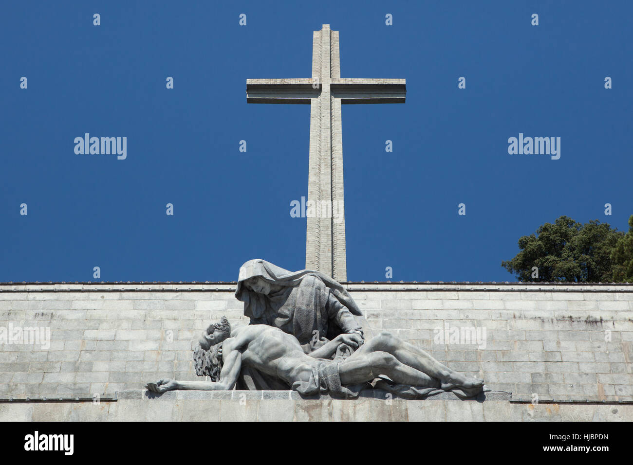 Die Kreuzkirche und die Pieta des spanischen Bildhauers Juan de Avalos über dem Haupteingang an der Basilica De La Santa Cruz (Basilika des Heiligen Kreuzes) im Valle de Los Caídos (Tal der gefallenen) in der Nähe von Madrid, Spanien. Stockfoto