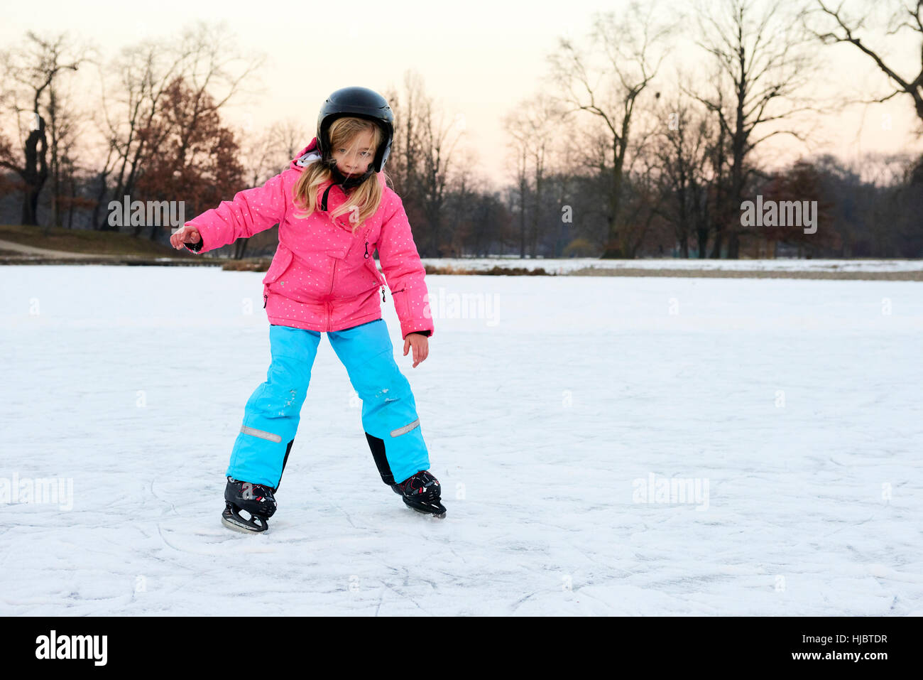 Glückliche kleine Mädchen Eislaufen im Winter im Freien, Schutzhelm tragen Stockfoto
