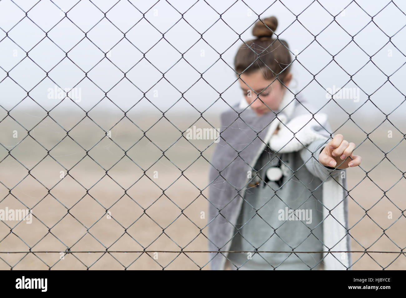 Mädchen hinter einem Zaun. Horizontalen Schuss mit natürlichem Licht. Stockfoto