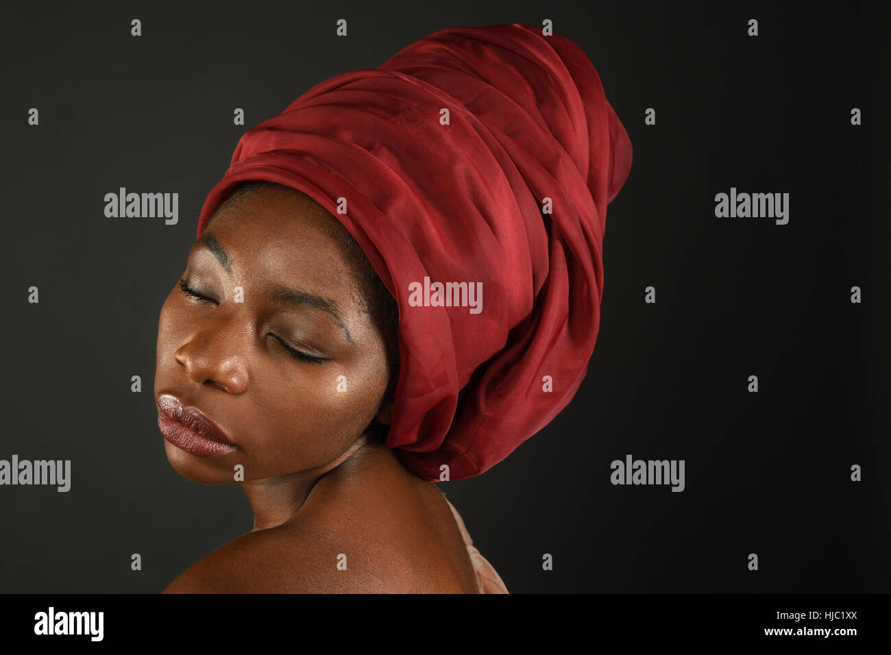 Porträt von Afrikanerin mit roten Turban auf dunklem Hintergrund isoliert Stockfoto