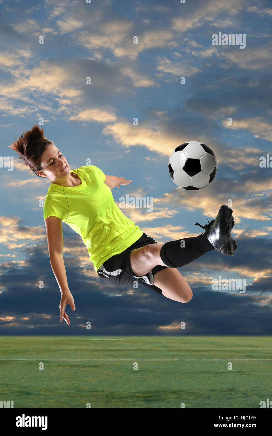 Weiblichen Fußballer treten Ball im Freien in der Abenddämmerung Stockfoto