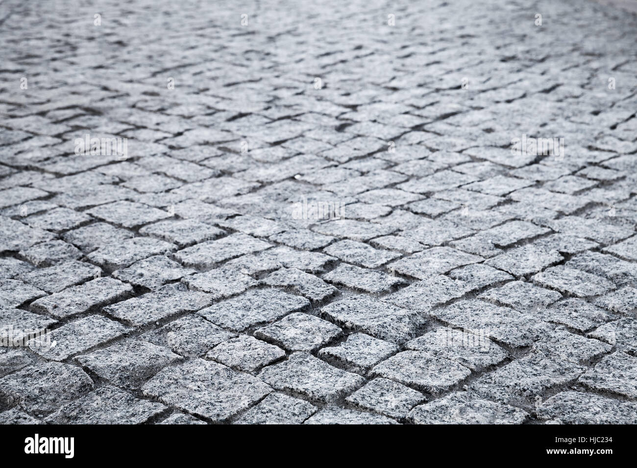 Dunkel grau gepflasterten Straße, Granit Stein Straßenpflaster, Hintergrundfoto mit selektiven Fokus Stockfoto