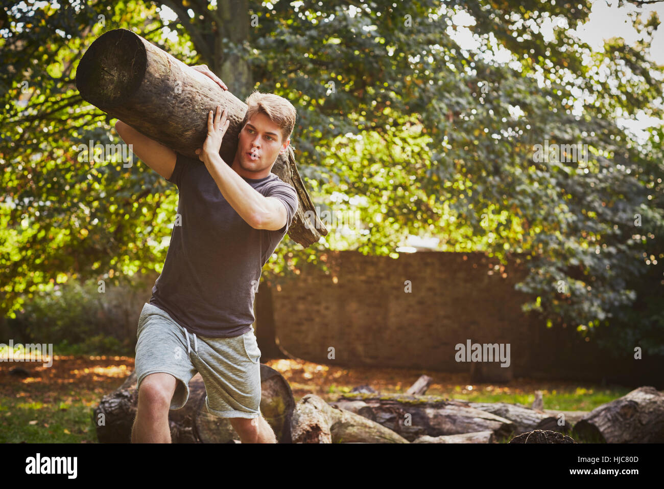 Junger Mann, Ausbildung, anhebende Baumstamm auf Schulter im park Stockfoto