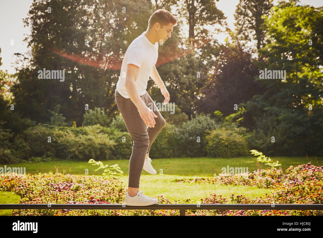 Mann, Ausbildung, balancieren auf einem Bein auf Park-Zaun Stockfoto