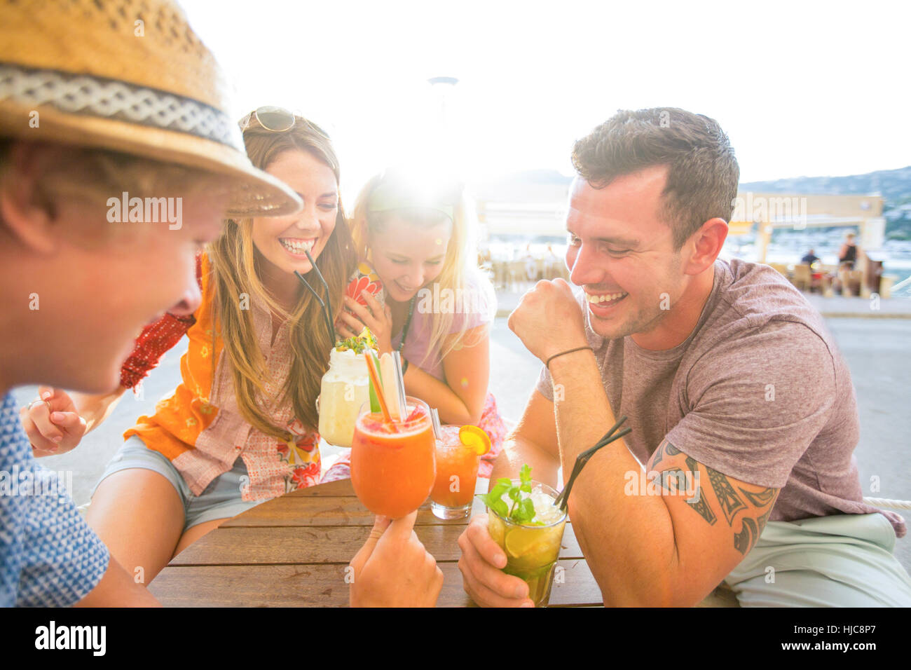 Zwei Erwachsene Paare lachen bei einem Cocktail im Waterfront Restaurant, Mallorca, Spanien Stockfoto