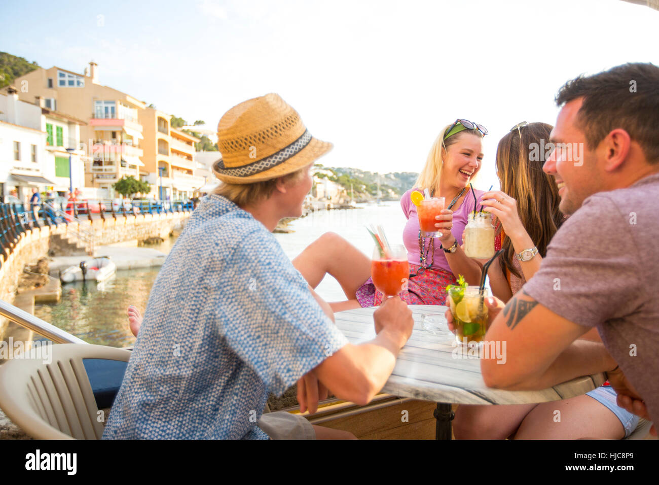 Zwei Erwachsene Paare teilen Cocktails im Restaurant am Meer, Mallorca, Spanien Stockfoto