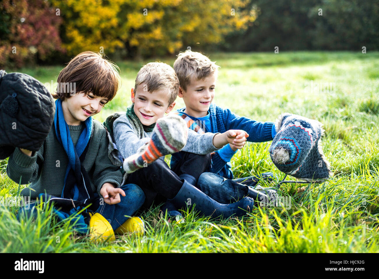 Drei Jungs sitzen zusammen im Feld, im Herbst Stockfoto