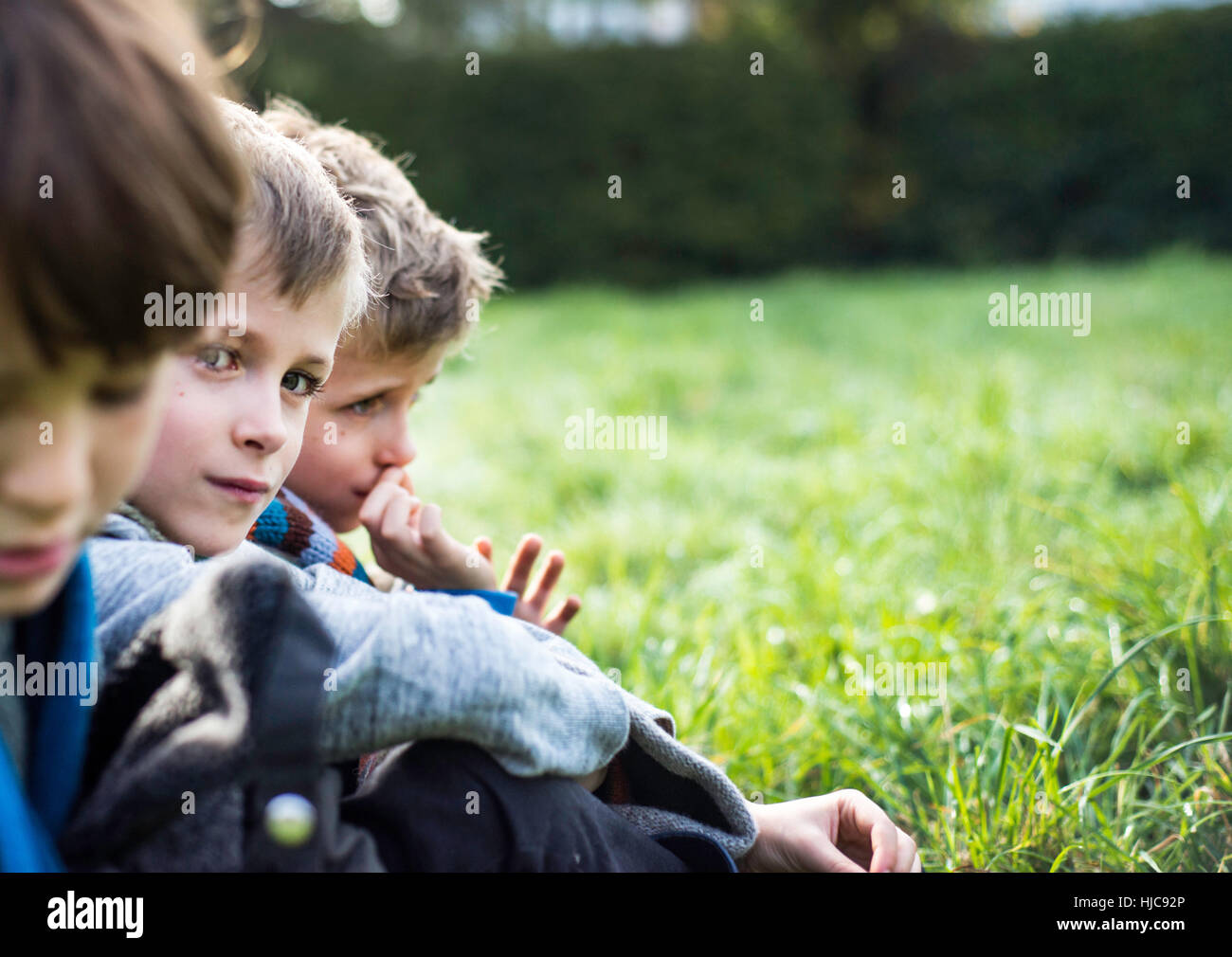 Drei Jungs sitzen zusammen im Feld, im Herbst Stockfoto