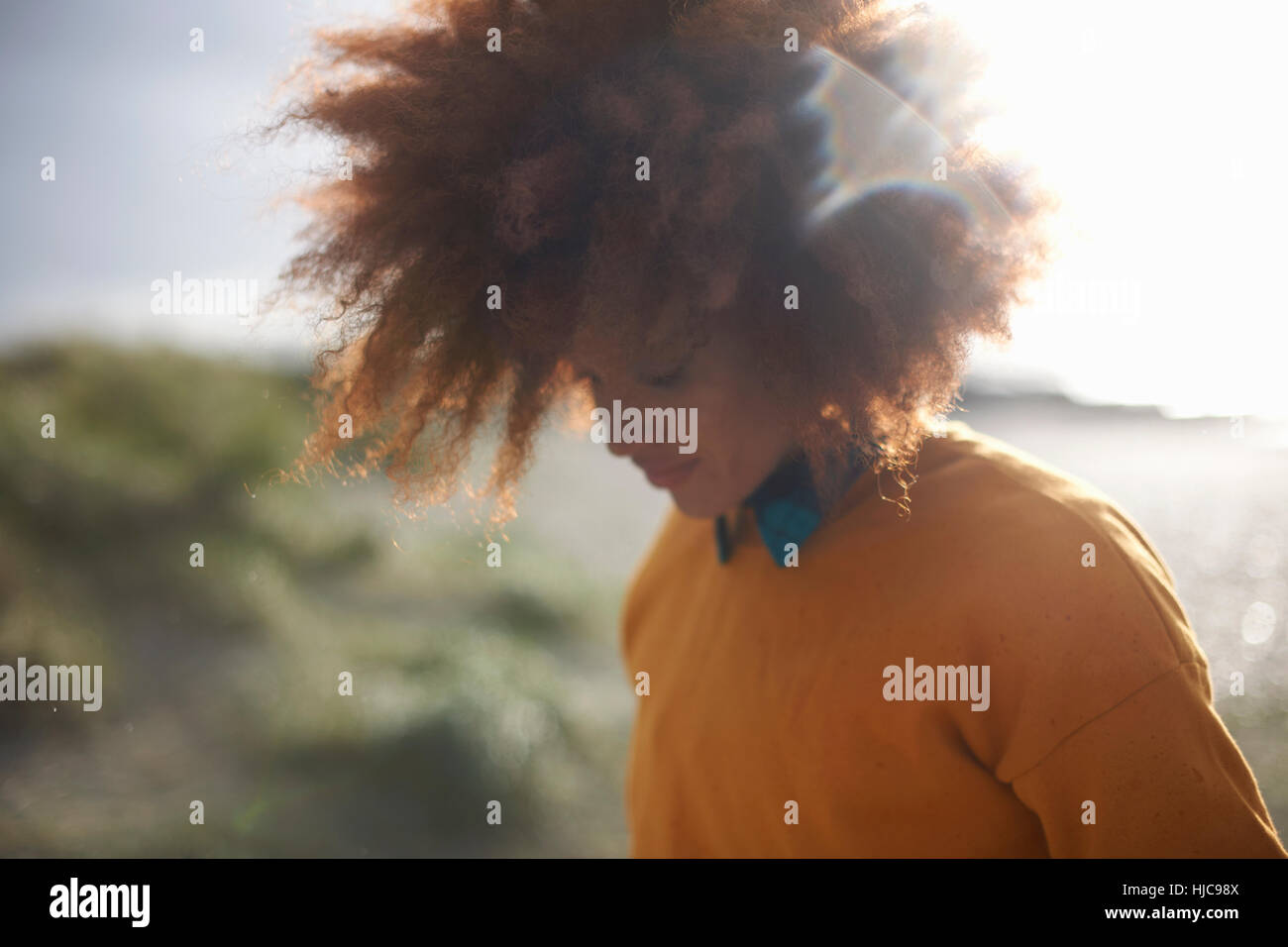 Frau mit Afro-Haar auf grasbewachsenen Düne Stockfoto