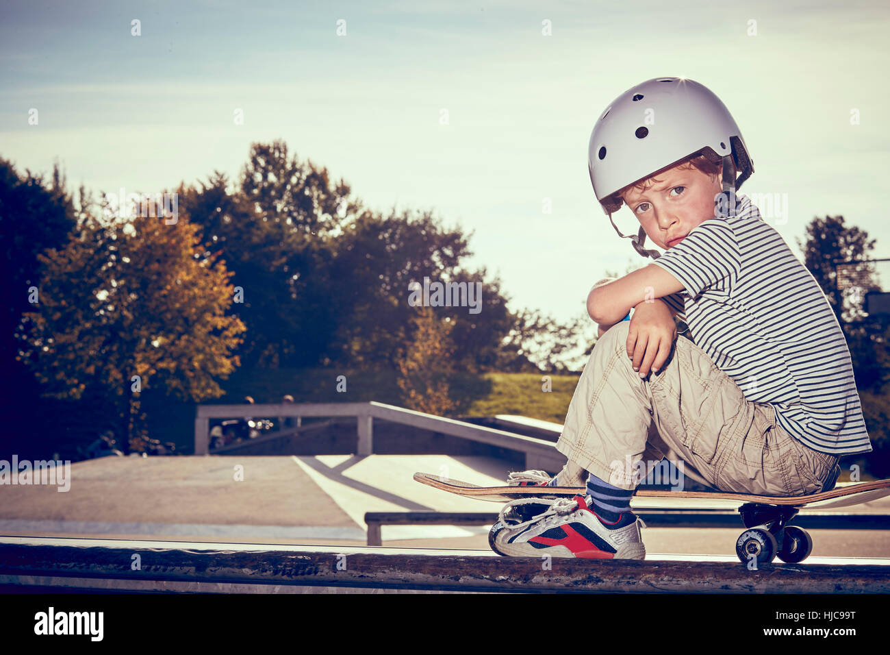 Junge sitzt auf Skateboard im park Stockfoto