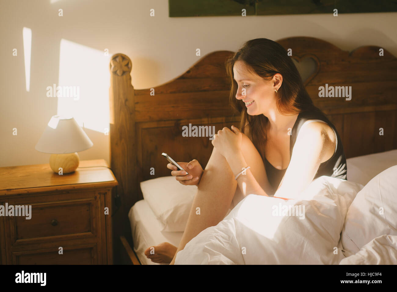 Frau mit Handy im Bett Stockfoto