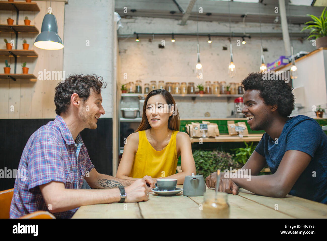 Frau und männliche Freunde im Chat gemeinsam im café Stockfoto