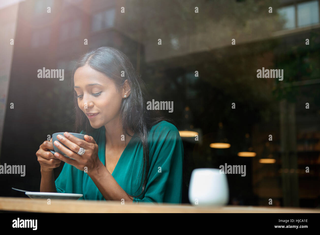 Mitte erwachsenen Frau in Café Fensterplatz blickte auf Kaffeetasse Stockfoto