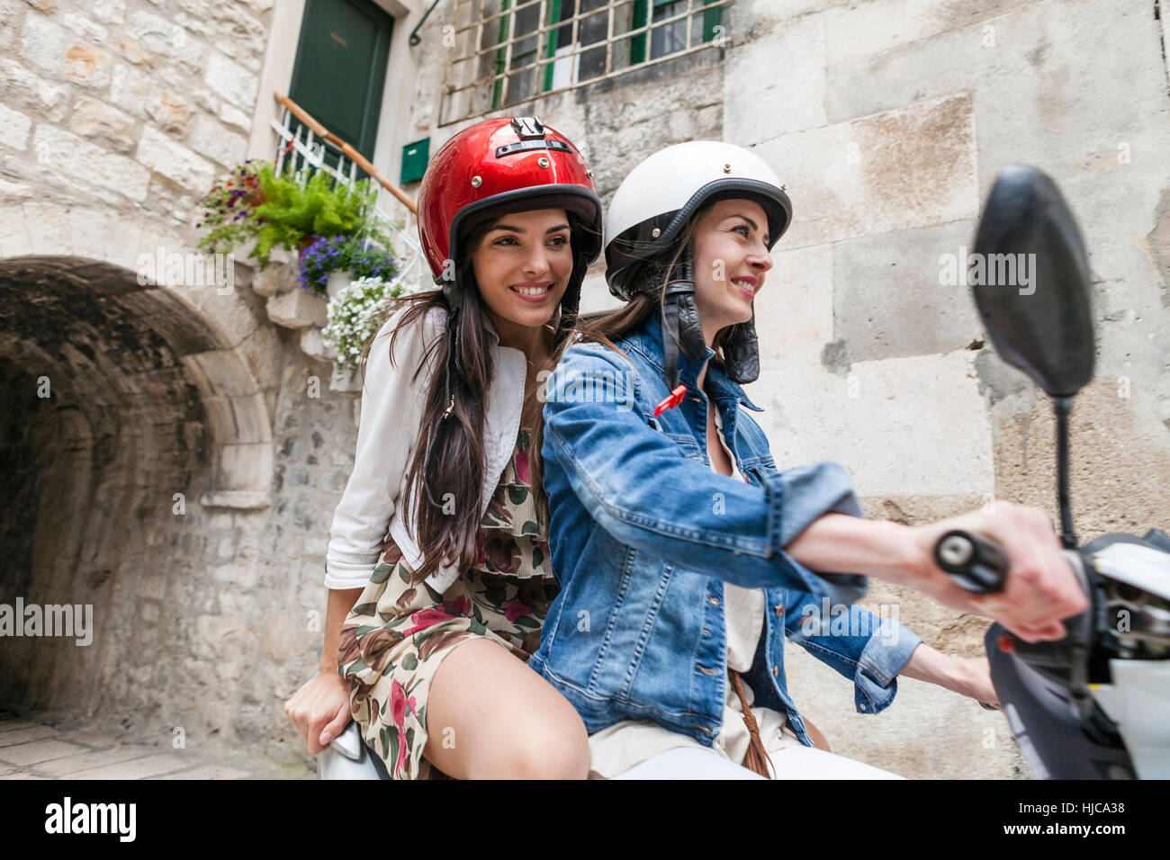 Weibliche Touristen fahren Moped durch Dorf, Split, Dalmatien, Kroatien Stockfoto