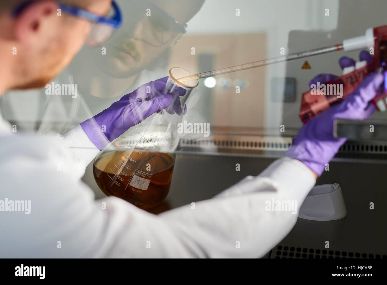 Wissenschaftler im Labor unter Verwendung elektronische Pipette in konischen Kolben Stockfoto