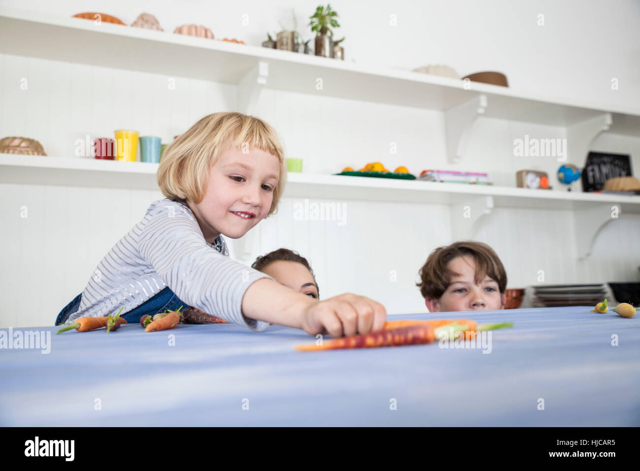 Junge Frau, jungen und Mädchen in Küche, herumalbern, blickte über Küchentheke Stockfoto