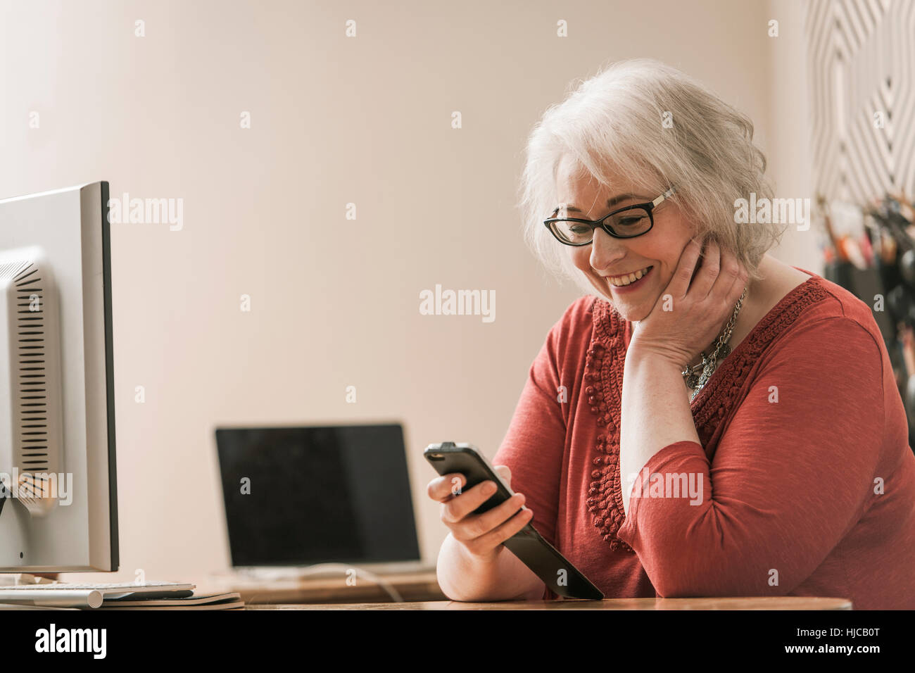 Frau, Lächeln, mit Handy am Schreibtisch Stockfoto