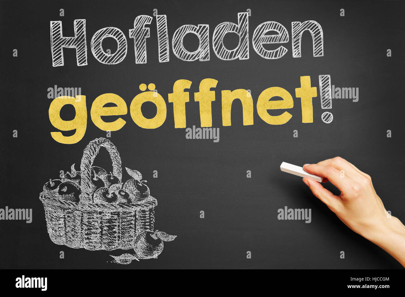 Hand, schreibt in Deutsch "Hofladen Geoeffnet!" (Hofladen geöffnet!) auf Tafel Stockfoto