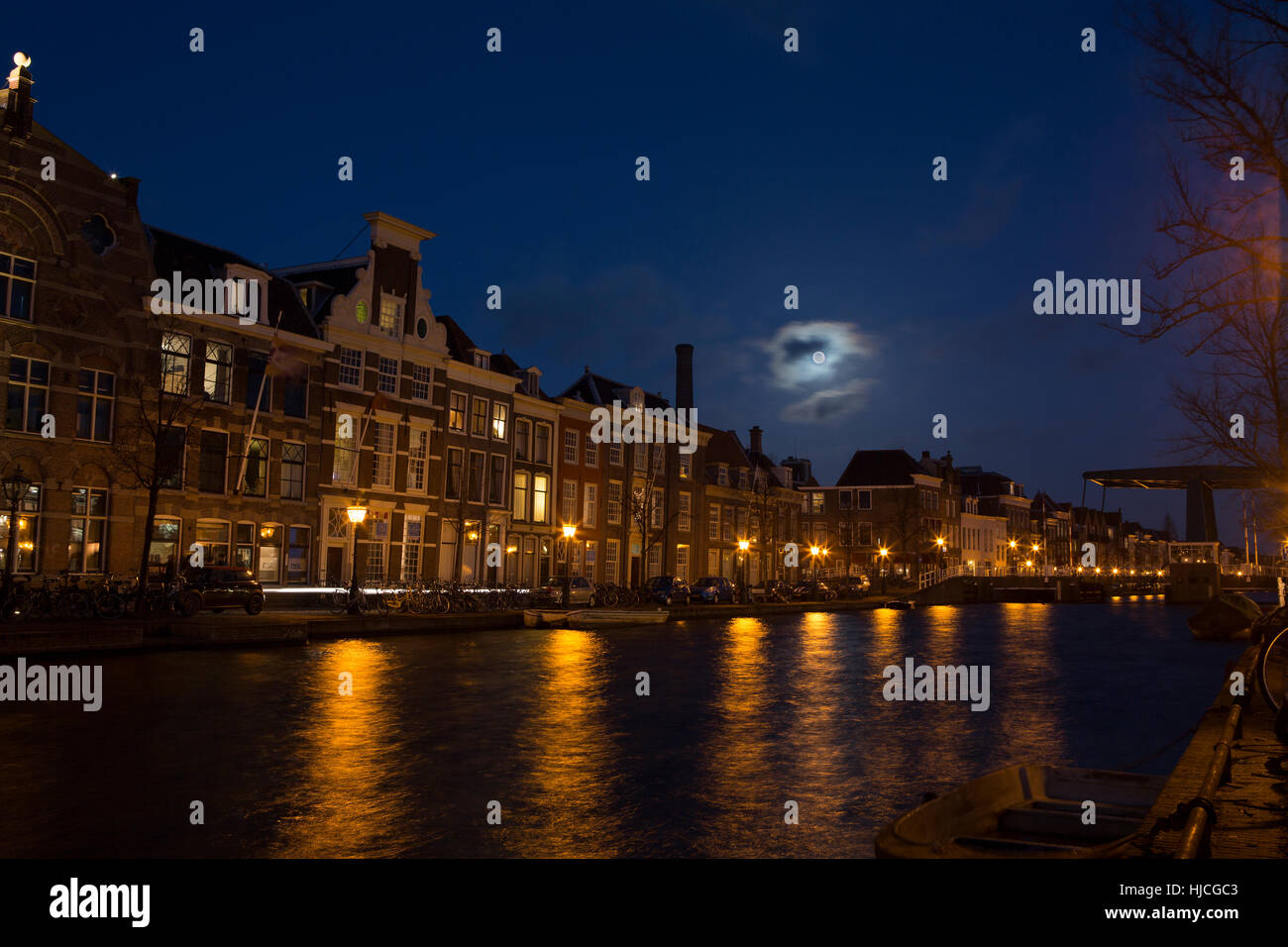 Nacht-Blick auf einen Kanal in der niederländischen Universität Stadt Leiden. Teilweise verdeckt der Mond an einem Winter-Abend mit Straße Licht-Reflektionen im Wasser. Stockfoto