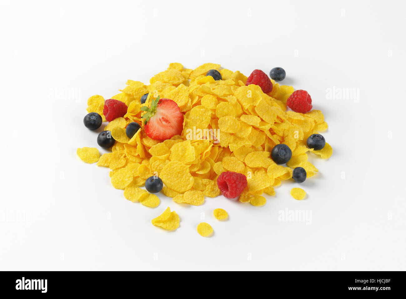 Haufen von Cornflakes mit Beeren auf weißem Hintergrund Stockfoto