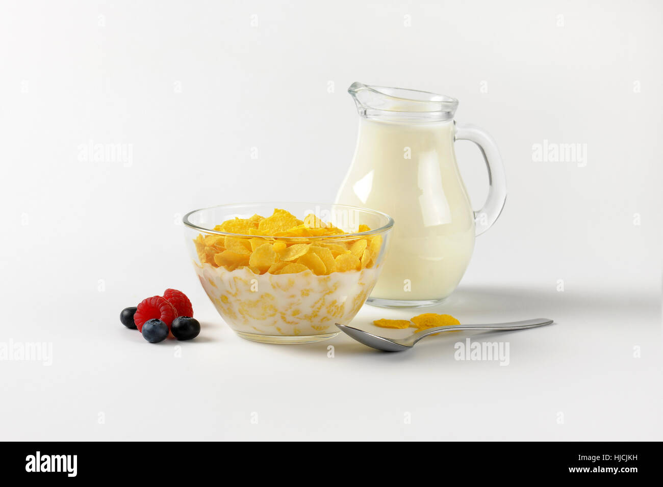 Schüssel mit Cornflakes und Krug Milch auf Wollweiß Hintergrund mit Schatten Stockfoto